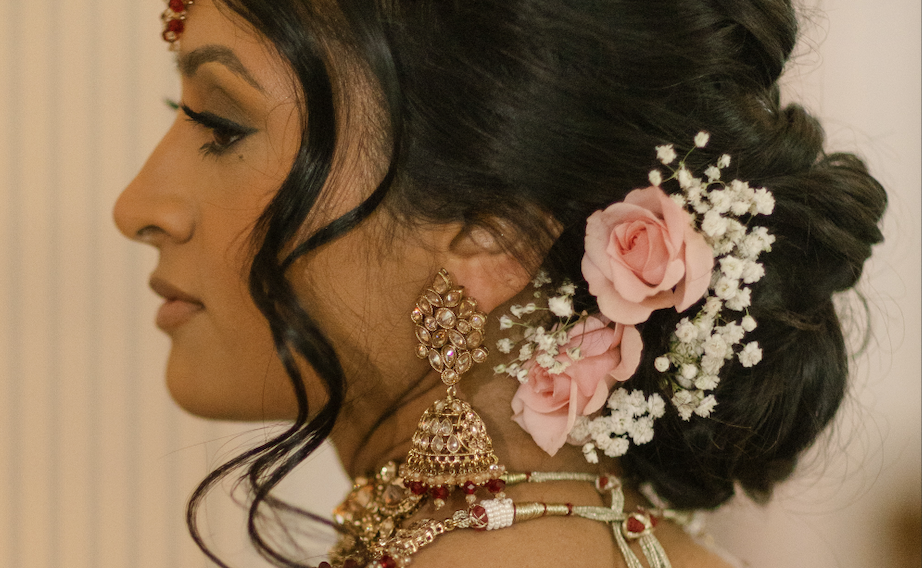Bride wearing a low wedding updo with real pink roses flowers and baby’s breath