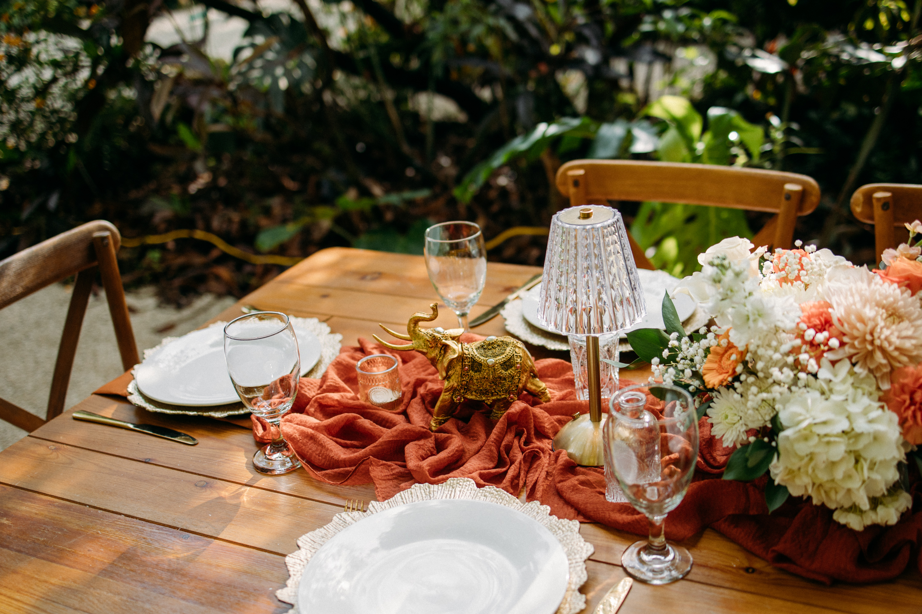 Outdoor wedding reception table with floral centerpieces, place settings, and candles at the Hindu wedding in Homestead, Florida.