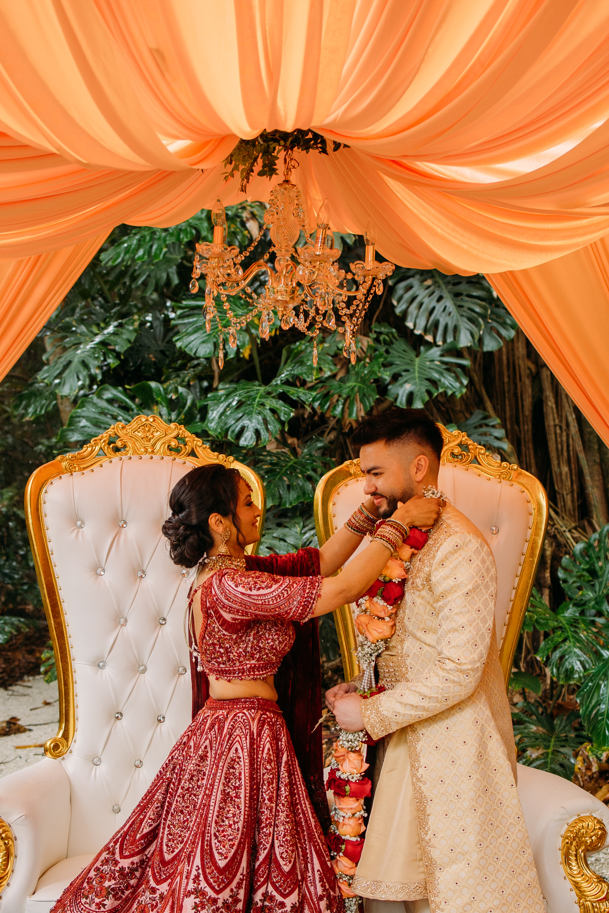 Bride placing a floral garland around the groom during their Hindu wedding ceremony in Homestead, Florida.